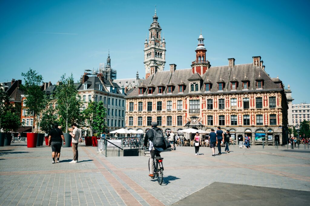 Lively city square in Lille with historic architecture and people enjoying a sunny day.